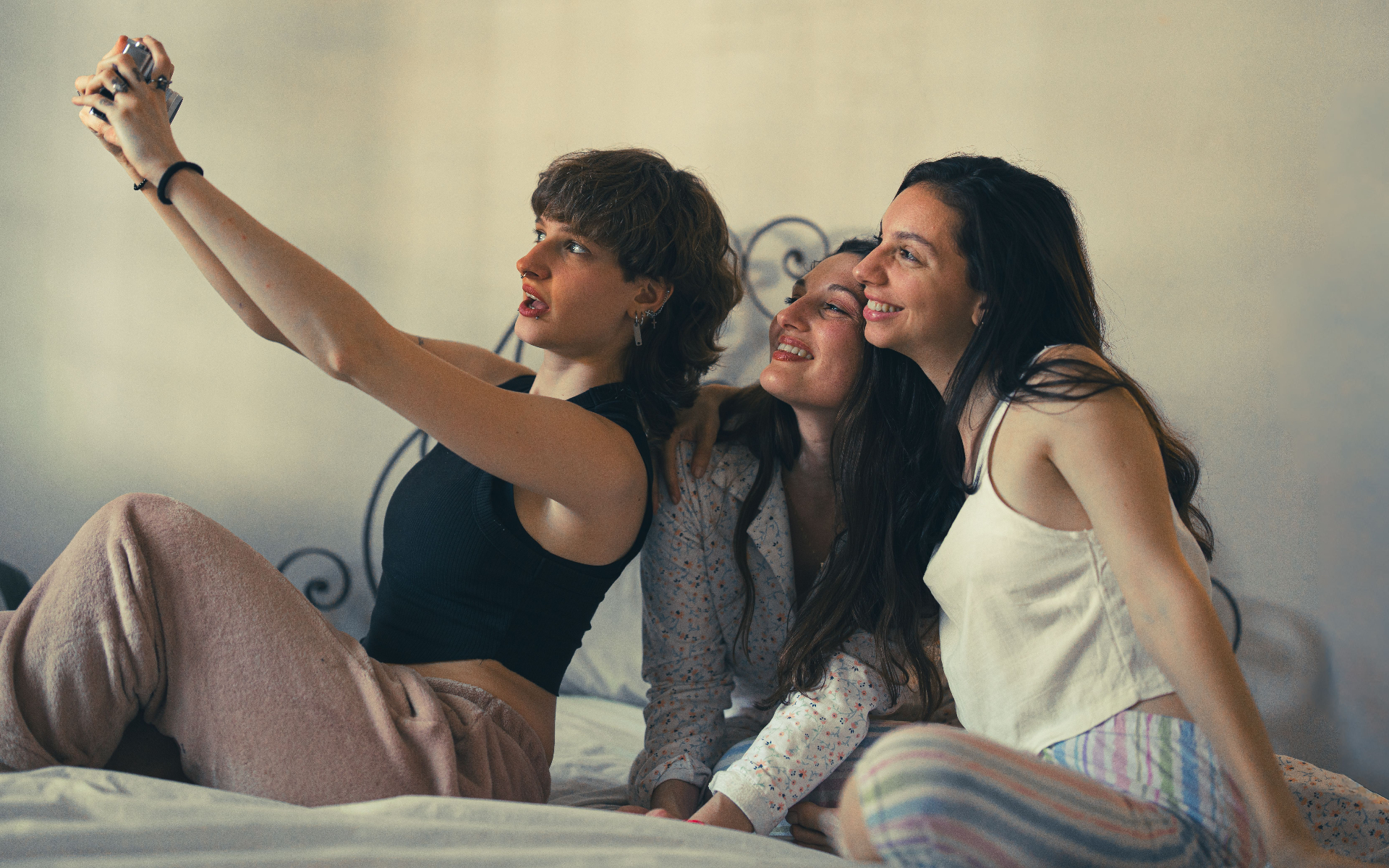 three women laughing together while taking a selfie